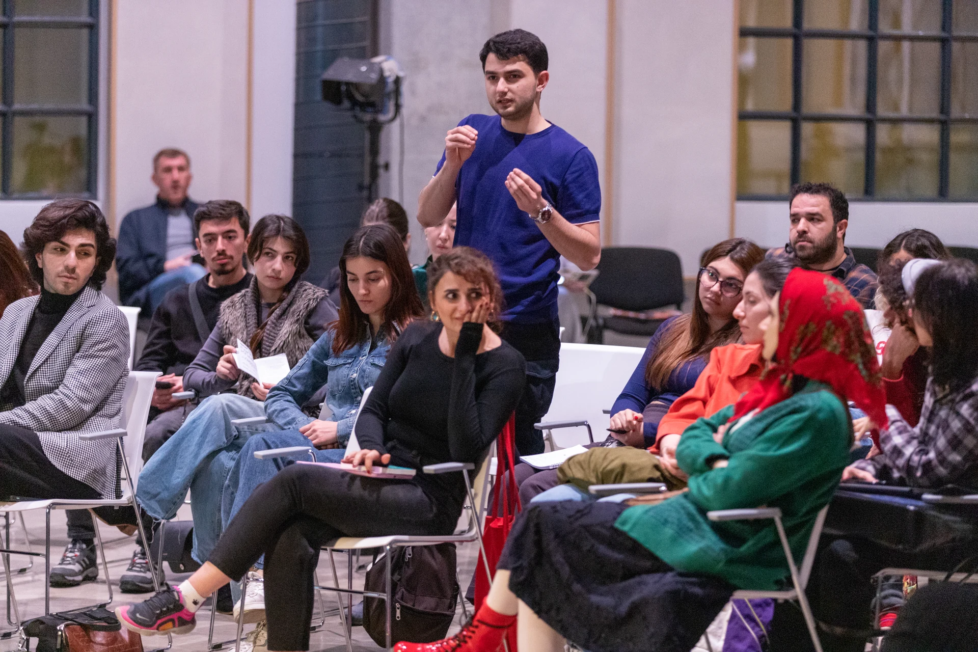 A course participant asks a question while the surrounding audience listens to the discussion.