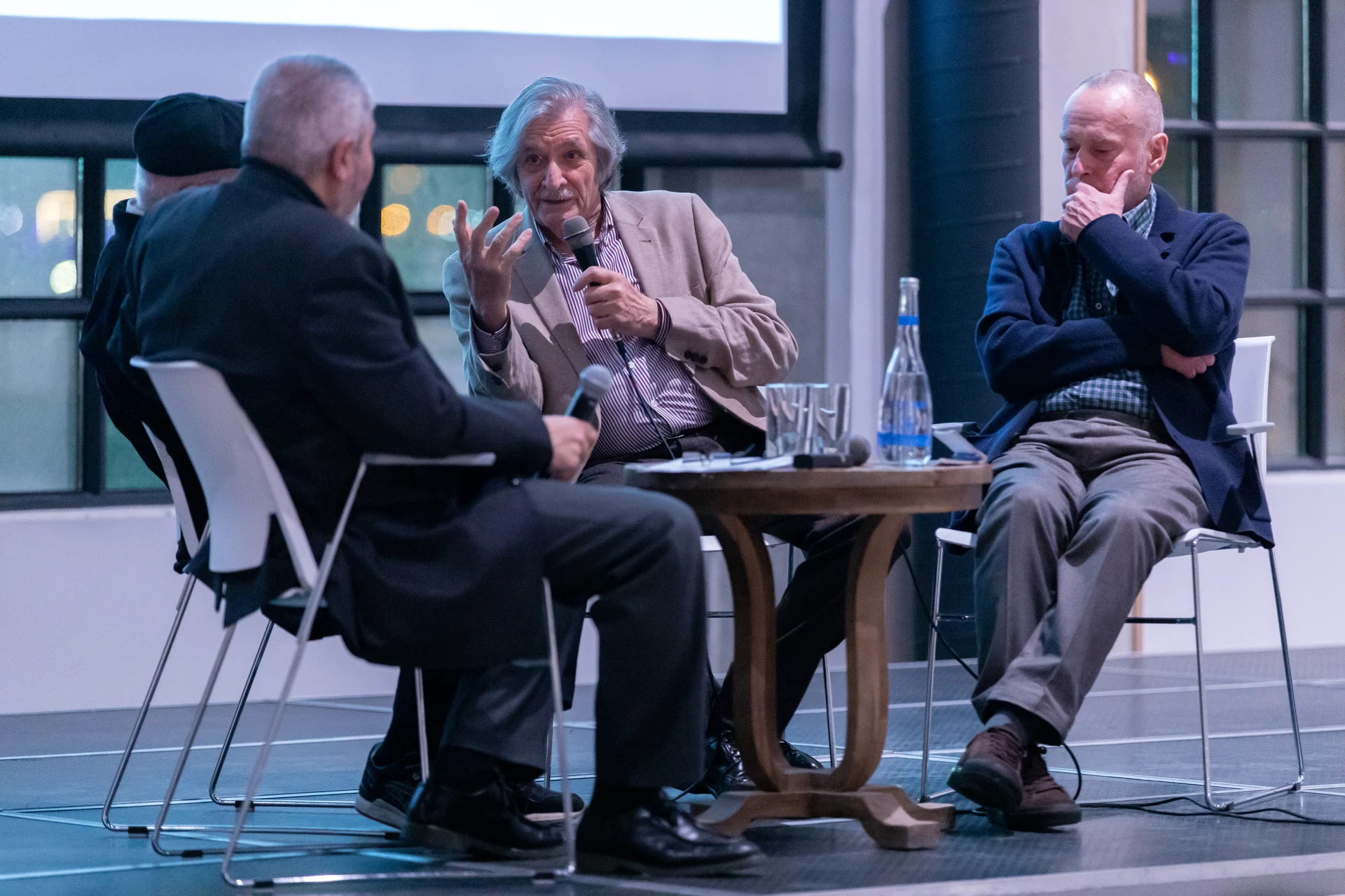 Farhad Khalilov speaks into a microphone as the other panellists listen at the creative evening.