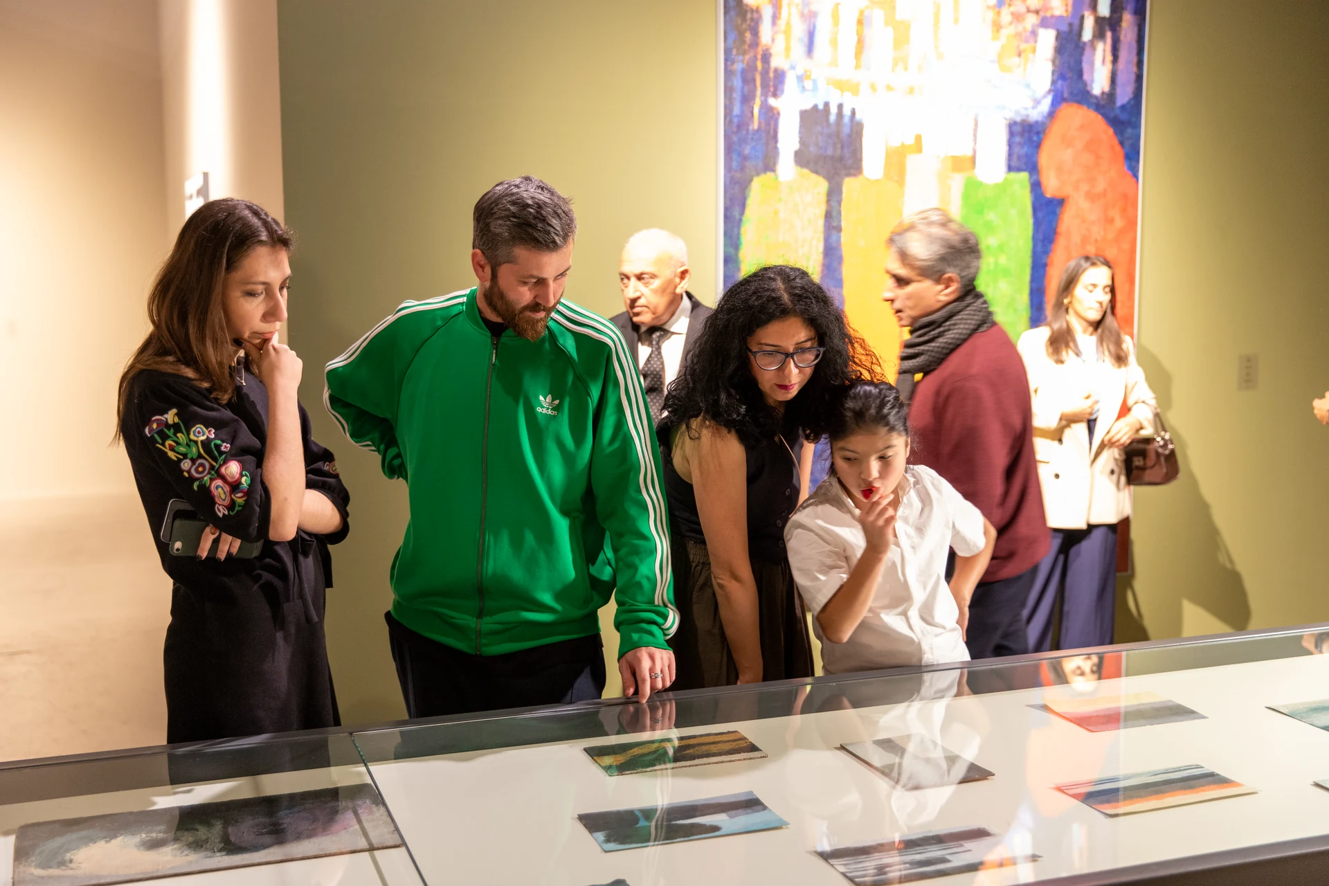 Opening visitors lean over the display case to look closely at the exhibited graphic works.