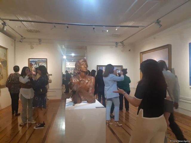 Visitors among paintings and a portrait bust at Heydar Aliyev: 100 Favourite Works in the Azerbaijan National Museum of Art.