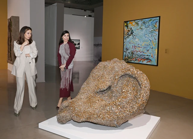 Visitors talking beside a sculpture and paintings at the opening of Once a Sea in Baku in April 2025.