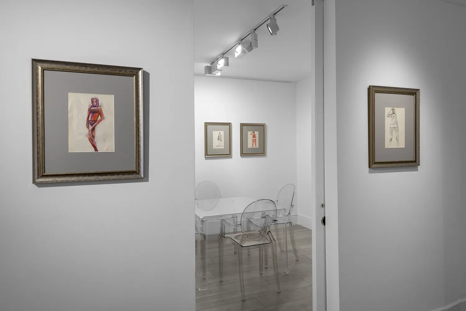 An adjoining room at The New Verge, with framed works on paper installed around a table and transparent chairs.