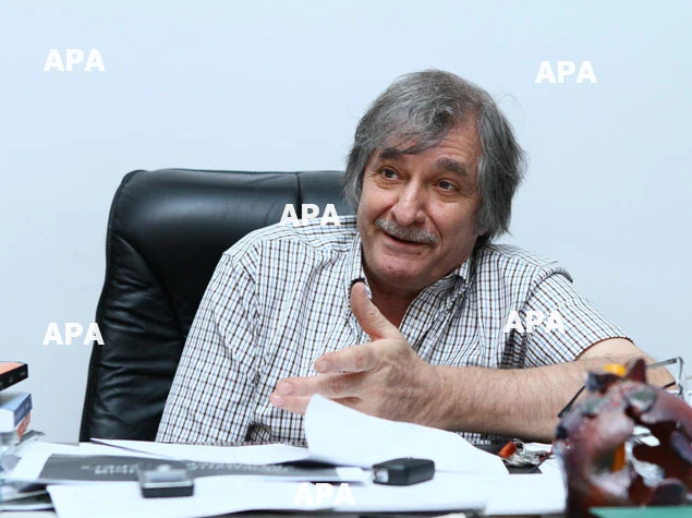 Farhad Khalilov smiling and extending his hand while speaking at his desk.