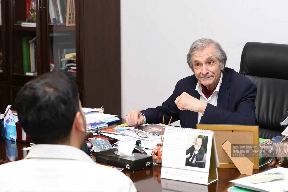 Nihat Pir seen from behind while Farhad Khalilov speaks from the other side of the desk.